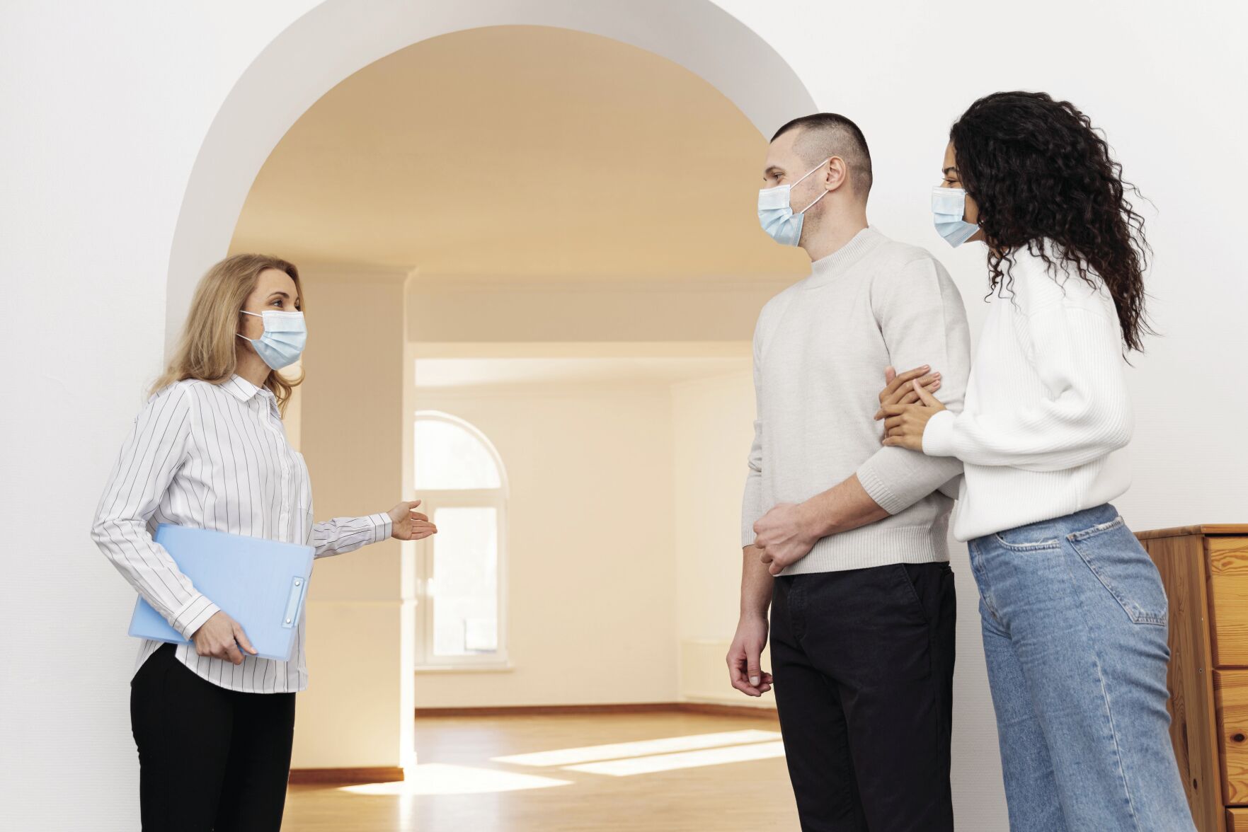 female-realtor-with-medical-mask-showing-couple-new-house.jpg